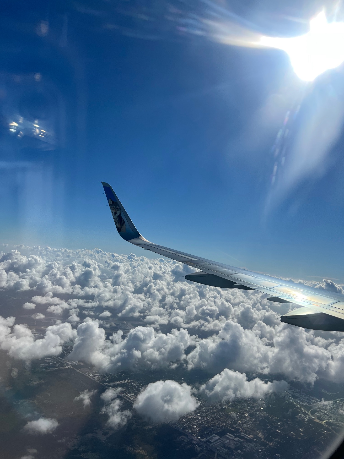View from an aircraft wing above sunlit clouds